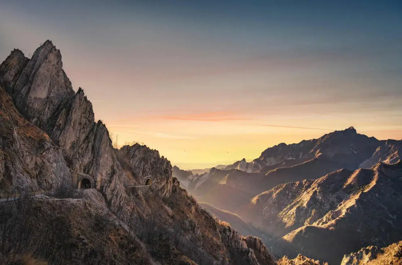 Albe rosate sulle Alpi Apuane, con gallerie scavate nella roccia che si aprono su valli profonde.