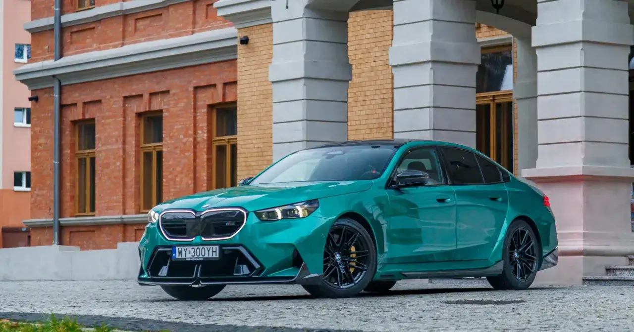 Mocne m5 bmw w kolorze zielonym, zaparkowane przed zabytkową kamienicą.