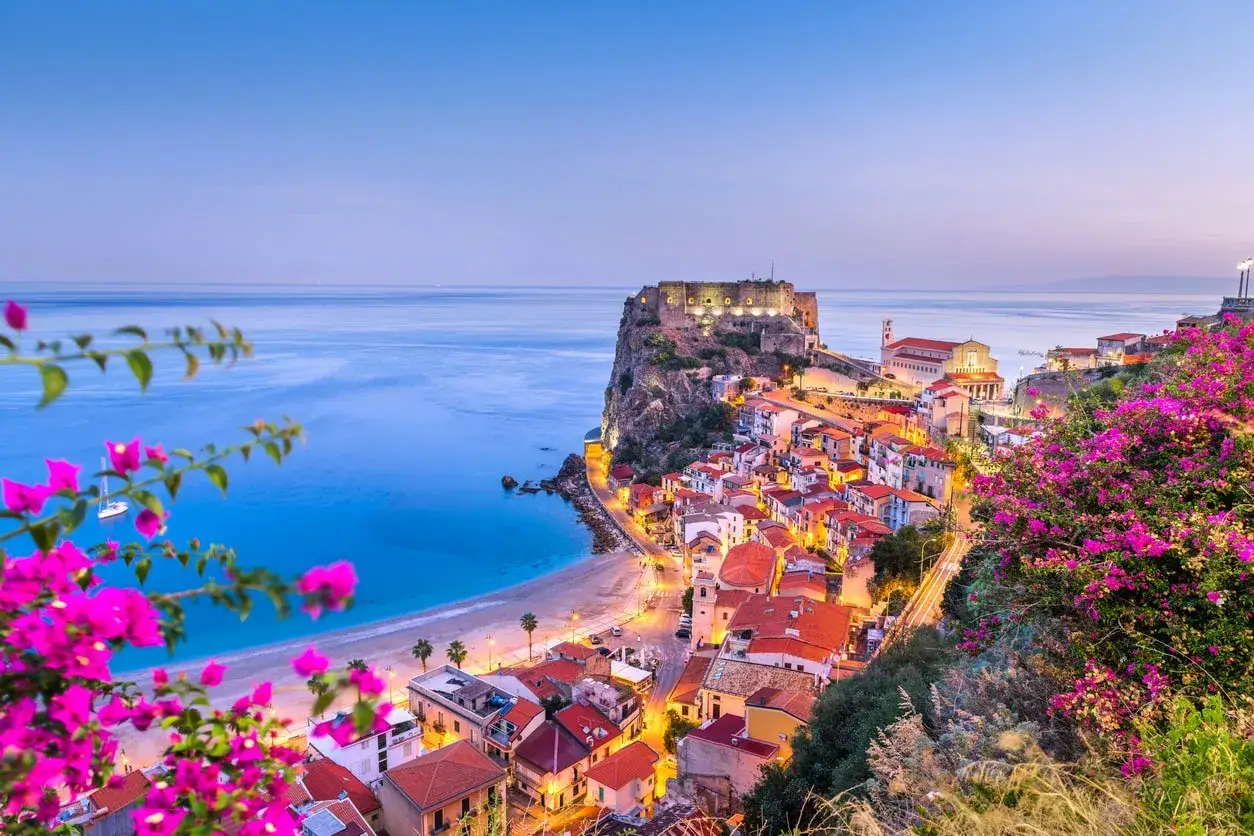 Scilla, uno dei posti belli in Calabria, con il castello arroccato, case colorate e fiori fucsia che incorniciano il mare blu.