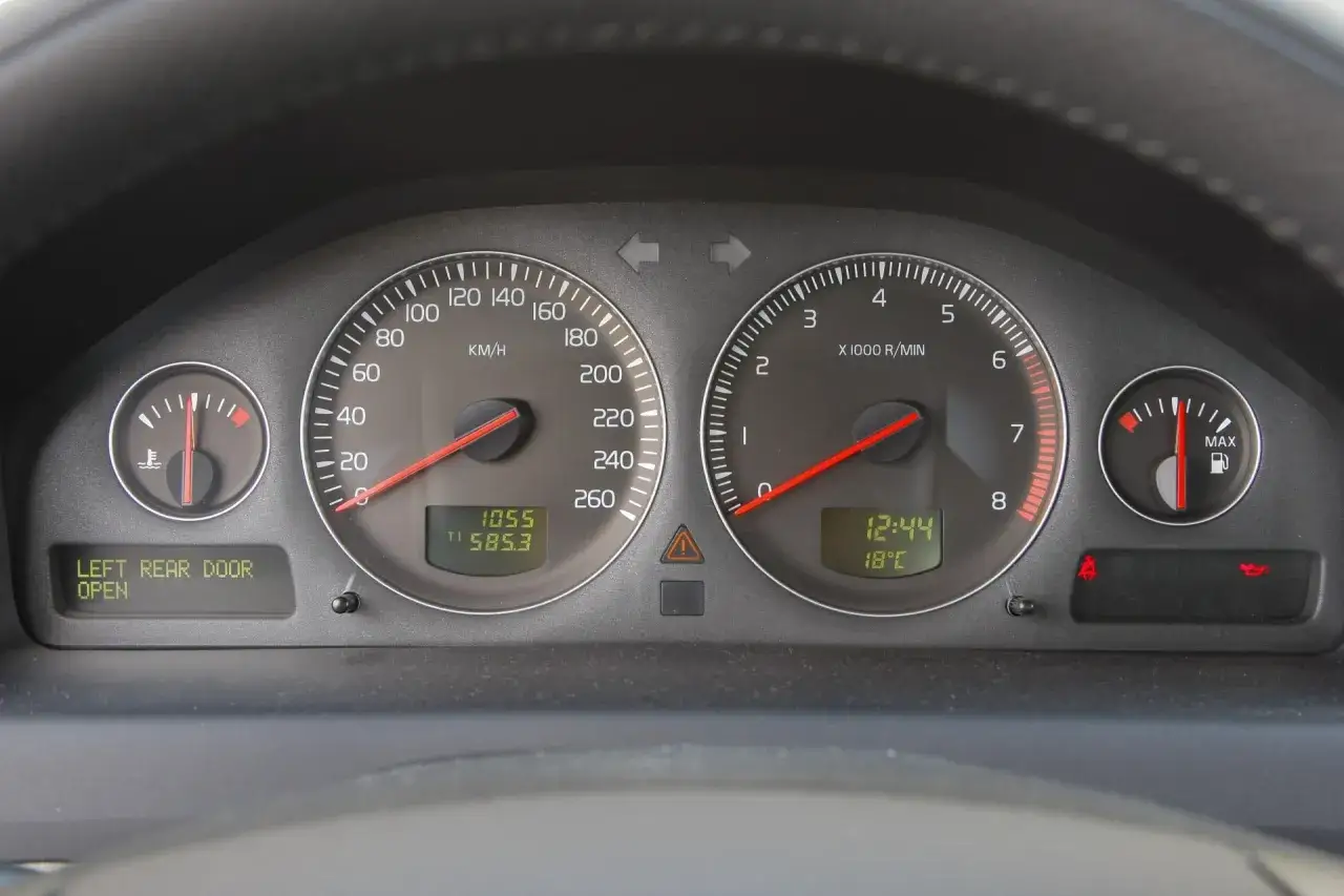 Deska rozdzielcza Volvo S60. Widoczne zegary, wskaźniki i wyświetlacz informujący o otwartych drzwiach. Czas na kasowanie inspekcji.