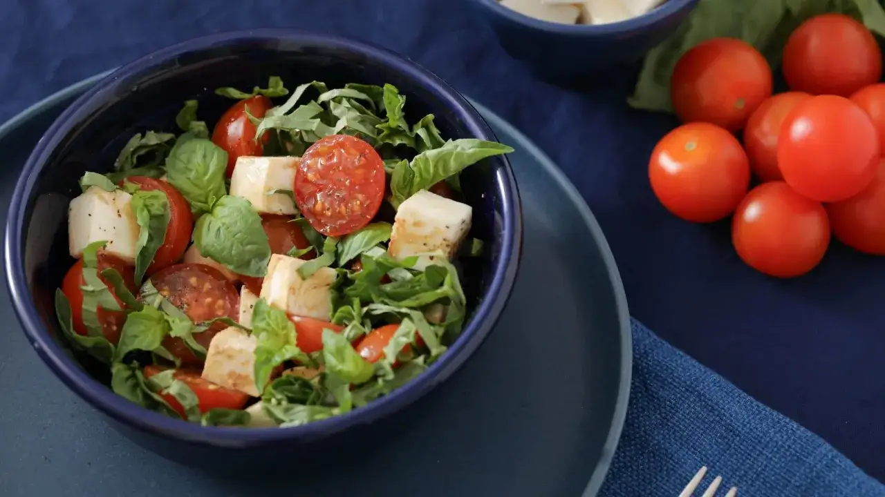 Sałatka z pomidorów i sera mozzarella, idealna na keto. Świeże pomidory i bazylia w niebieskiej misce.
