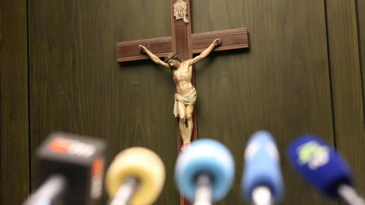 Kreuzigungsgruppe vor Mikrofonen, ein Symbol f&uuml;r die Beziehung zwischen Kirche und Staat in der &Ouml;ffentlichkeit.