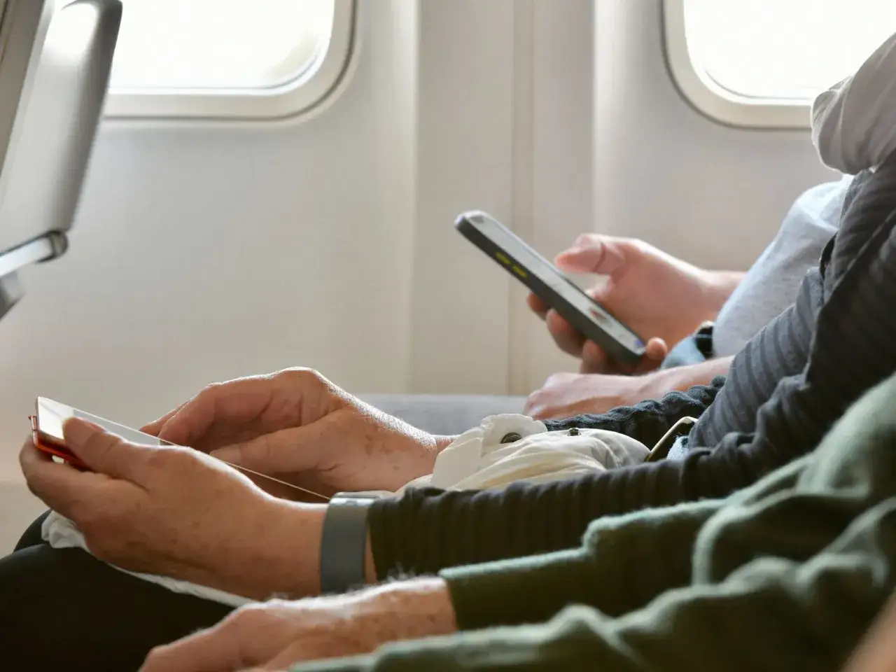 Pasażerowie w samolocie korzystają z telefonów. Czy w Ryanair jest wifi? Trudno stwierdzić, ale podróżni są zajęci swoimi urządzeniami.