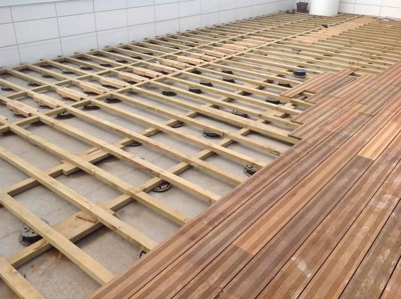 Structure en bois pour faire une terrasse. Des lambourdes sont posées sur des plots, prêtes à recevoir les lames de bois.