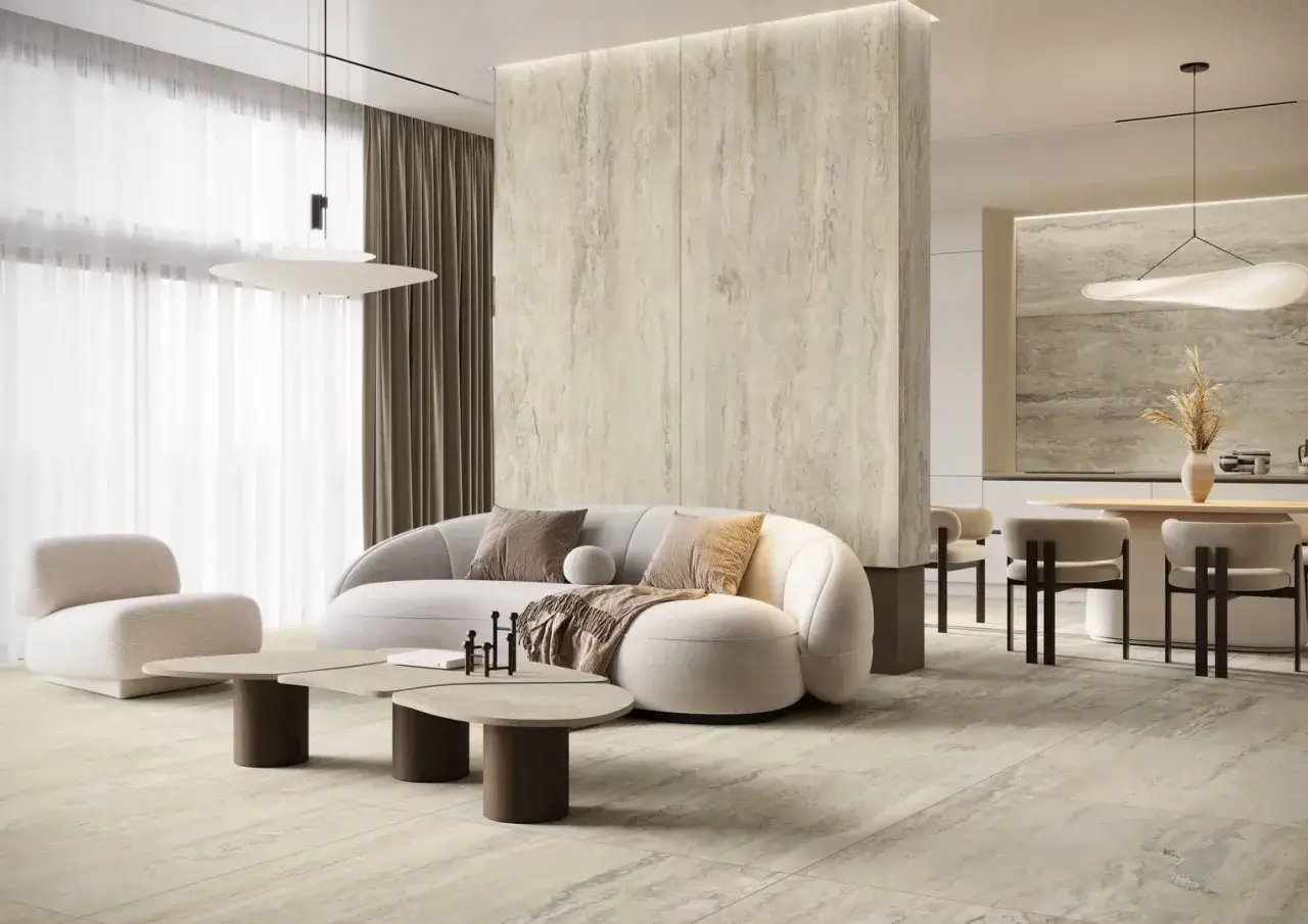 Nowoczesny salon z sofą i fotelami, gdzie podłoga i ściana centralna wykończone są naturalnym **trawertynem**, tworząc spójną, elegancką przestrzeń.