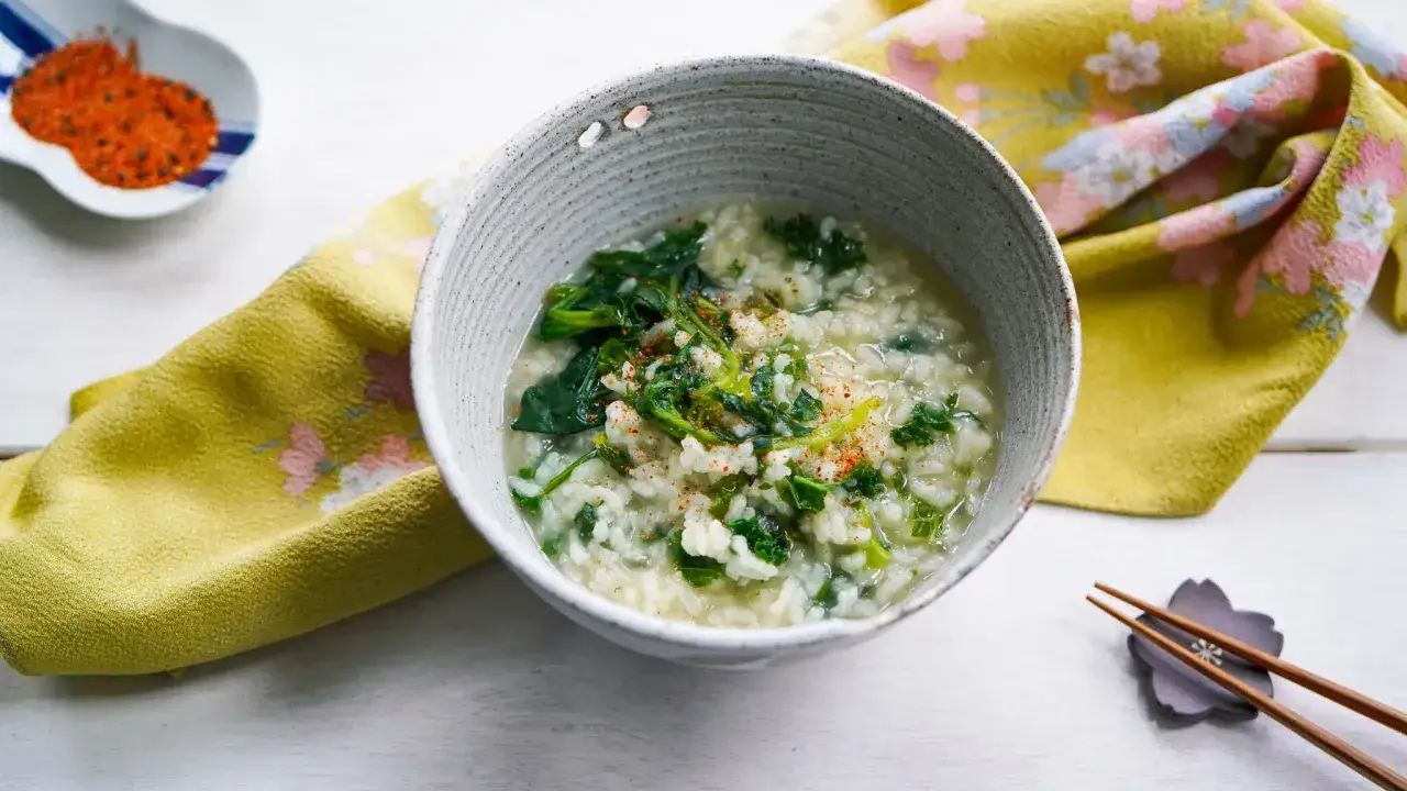 A comforting bowl of Japanese rice porridge recipe, also known as okayu, with fresh spinach and a sprinkle of chili flakes.