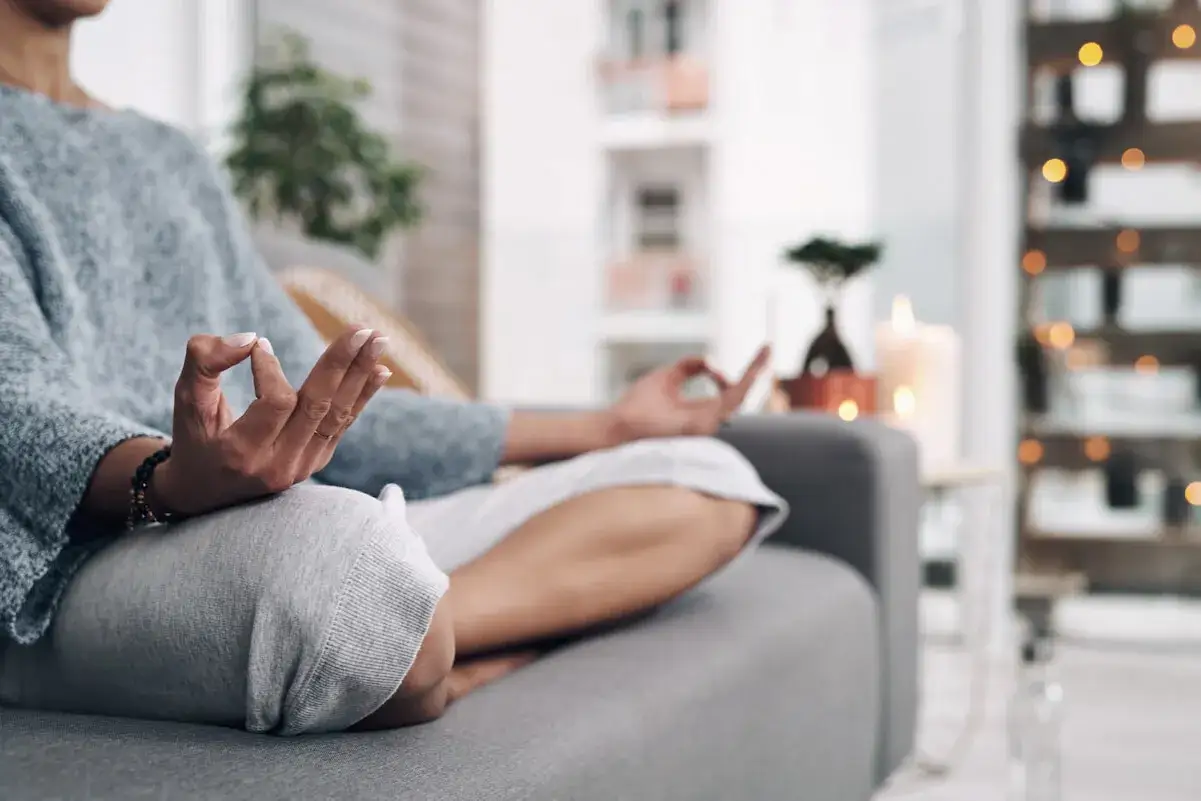Frau in bequemer Kleidung praktiziert Meditation, um Erdung zu finden. Sanfte Lichter und Kerzen schaffen eine beruhigende Atmosphäre.