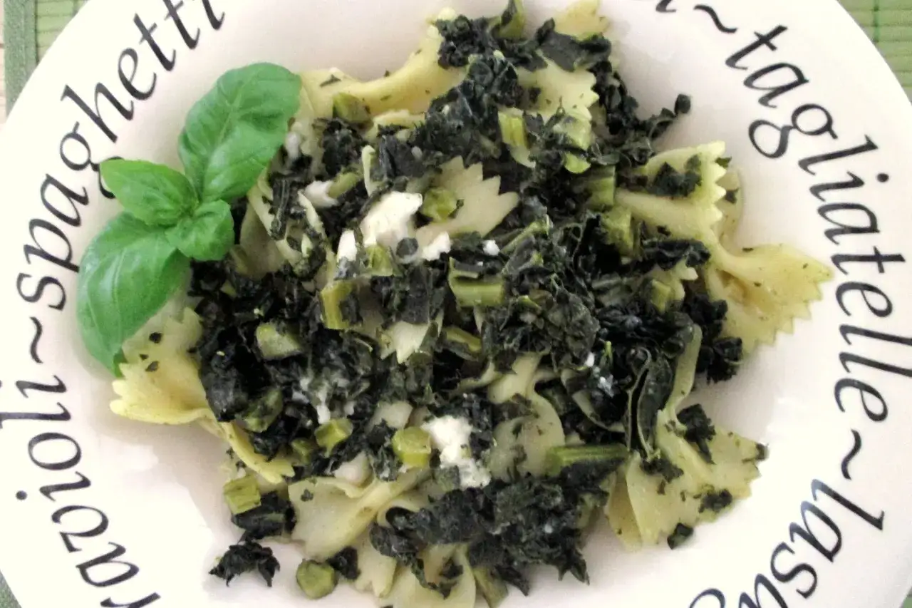 Farfalle con cavolo nero e ricotta, guarnite con basilico fresco. Un piatto semplice e gustoso.