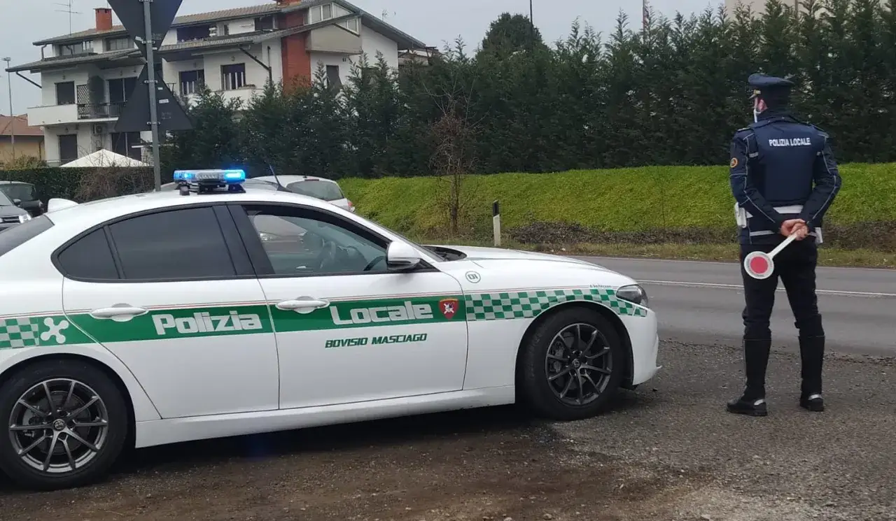 Agente di Polizia Locale con paletta ferma un veicolo. La scena suggerisce una possibile confisca veicolo o un controllo stradale.