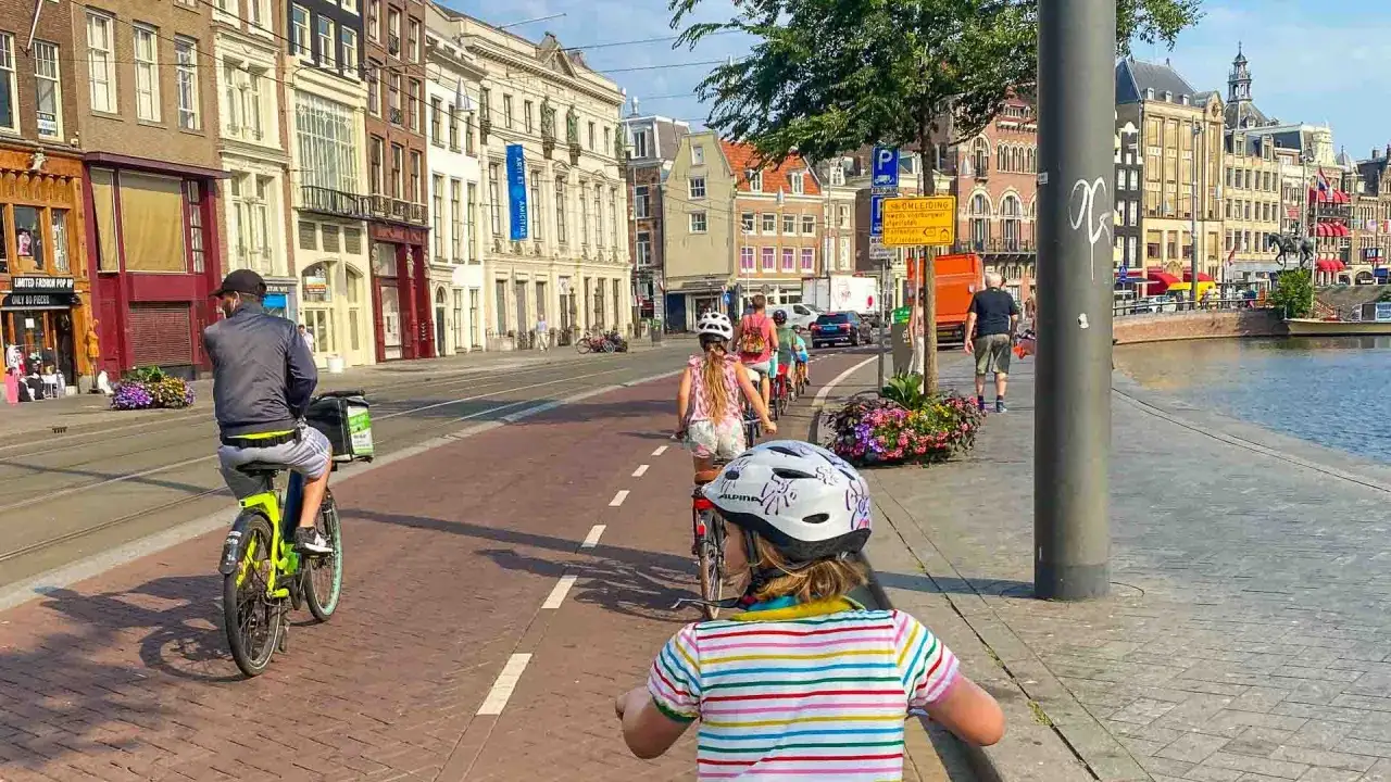 Familie radelt durch eine malerische Fahrradstadt in Deutschland, vorbei an historischen Geb&auml;uden und einem Kanal.