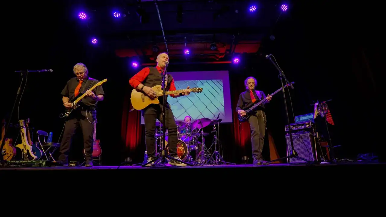 Un groupe rock canadien francophone en pleine performance, éclairé par des lumières violettes.