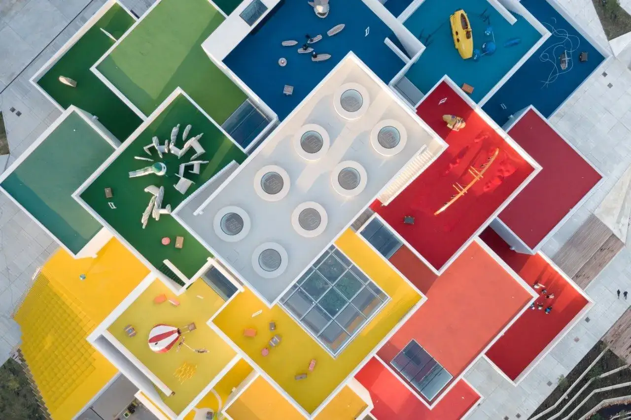 Kolorowe dachy Lego House w Billund, przypominające klocki, z placami zabaw i elementami architektonicznymi.