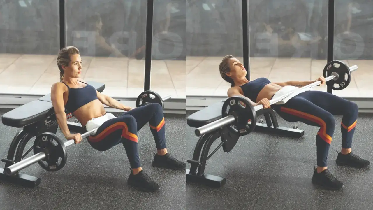 Frau macht einen Glute Bridge mit Langhantel auf einer Bank.