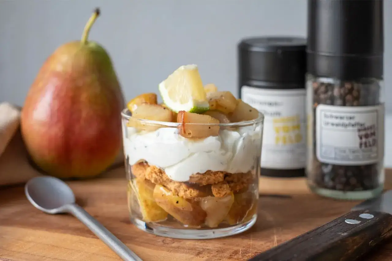 Schichtdessert mit karamellisierten Birnen, Joghurt und Keksbröseln. Ein köstlicher nachtisch birne, garniert mit Limette.