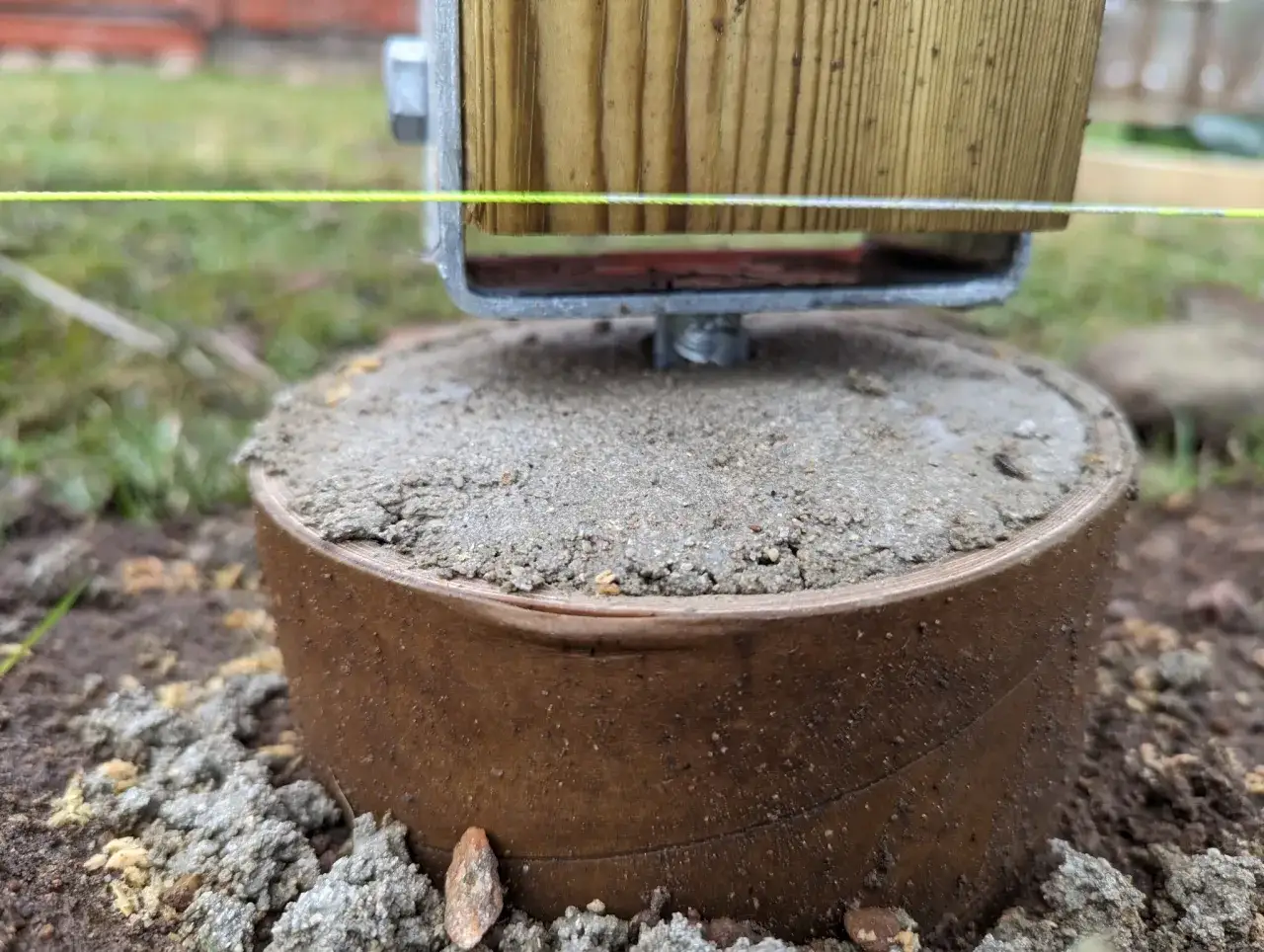 En nybyggd stolpe f&ouml;r ett staket vilar p&aring; en gjuten plint. En sn&ouml;rning visar h&ouml;jden.