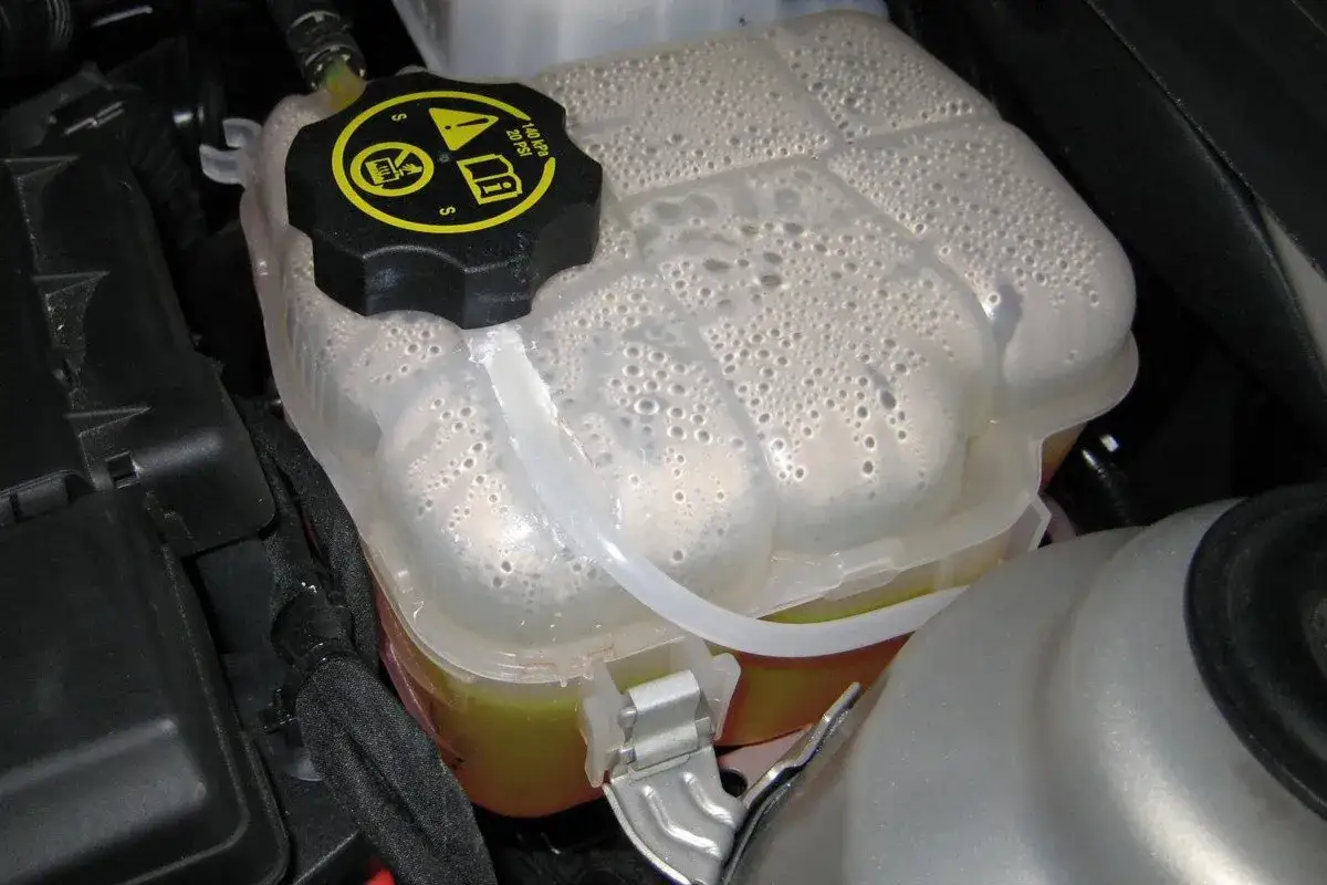 Dep&oacute;sito de anticongelante con burbujas y l&iacute;quido amarillo. El anticongelante protege el motor del sobrecalentamiento y la congelaci&oacute;n.
