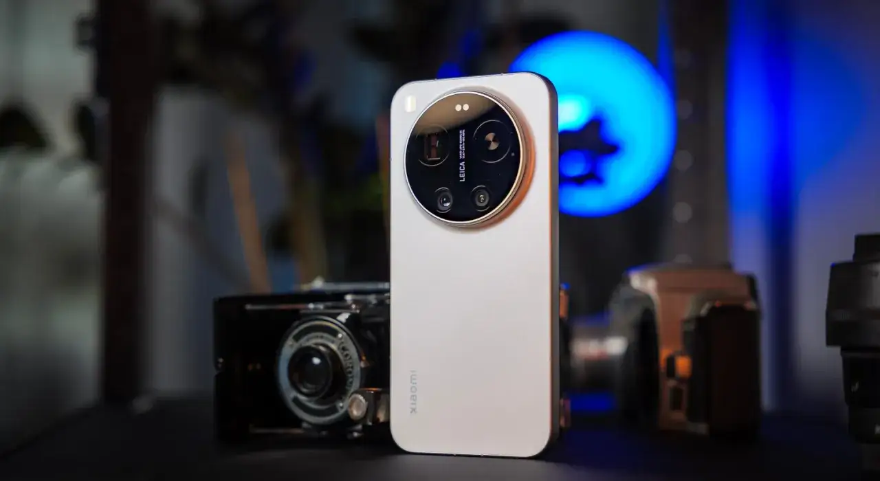 Srebrny Xiaomi z potr&oacute;jnym aparatem Leica, obok starego aparatu i obiektywu. Ten Xiaomi dobry aparat do fotografii.
