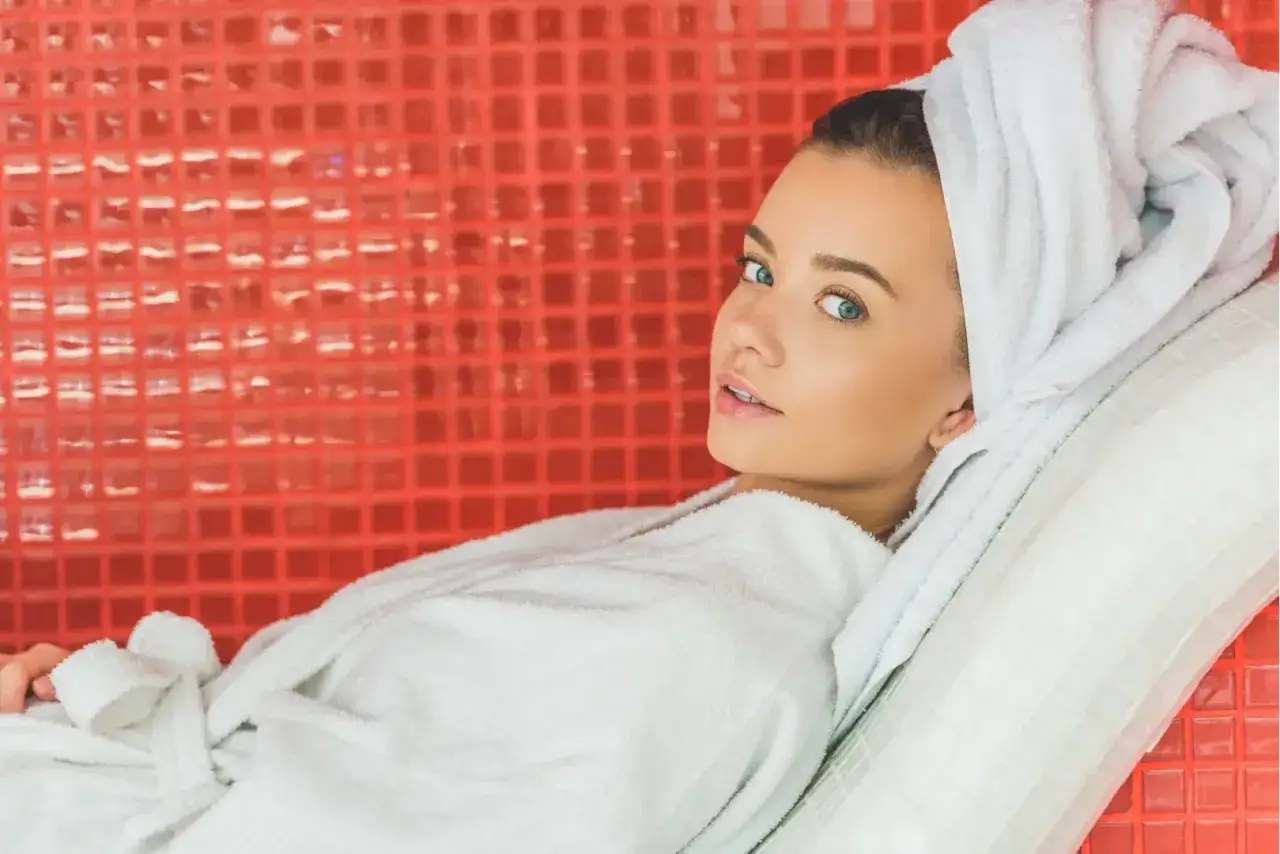 Relaxing woman in a white robe and towel, enjoying the infrared body wrap benefits.