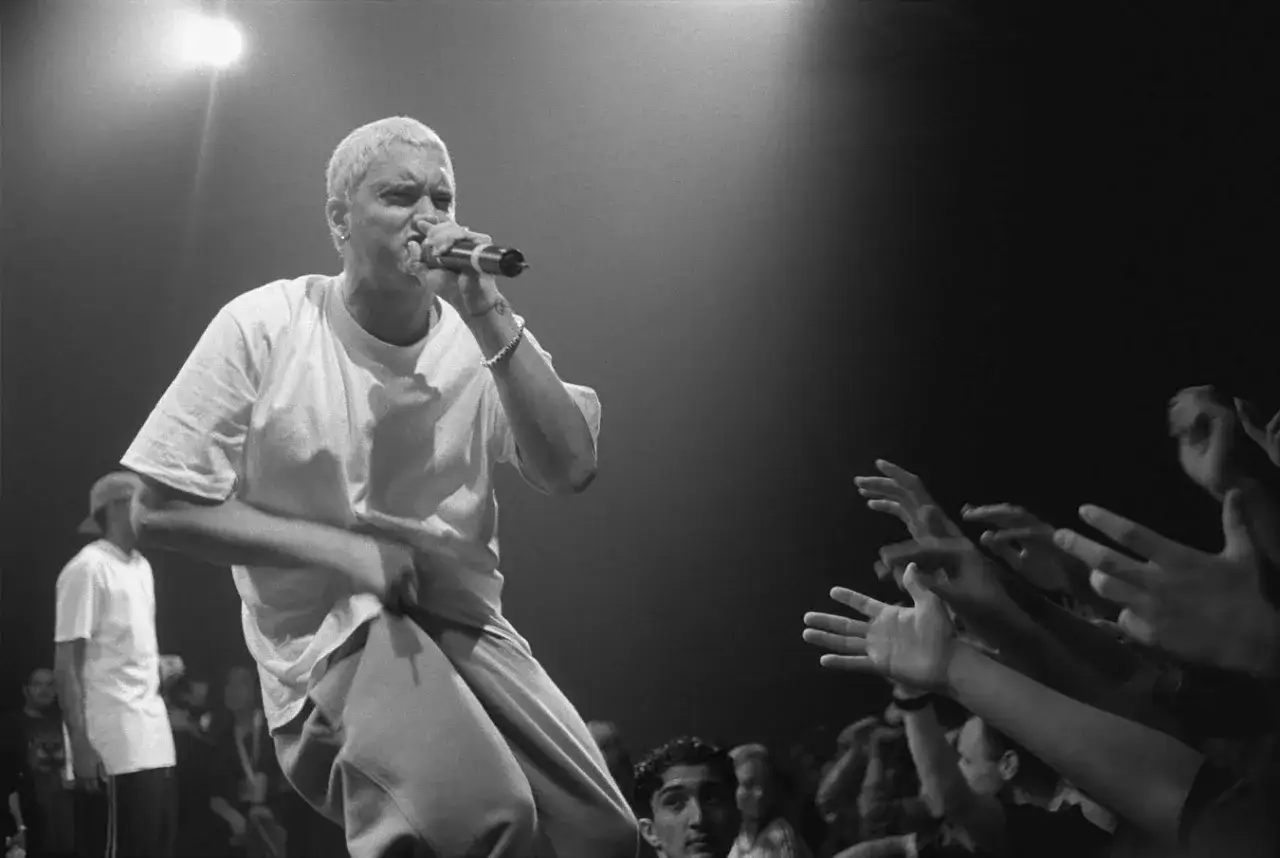 Eminem na scenie, tłum wyciąga ręce. Ile lat ma Eminem? Tego nie wiemy, ale jego energia jest niezmierzona.