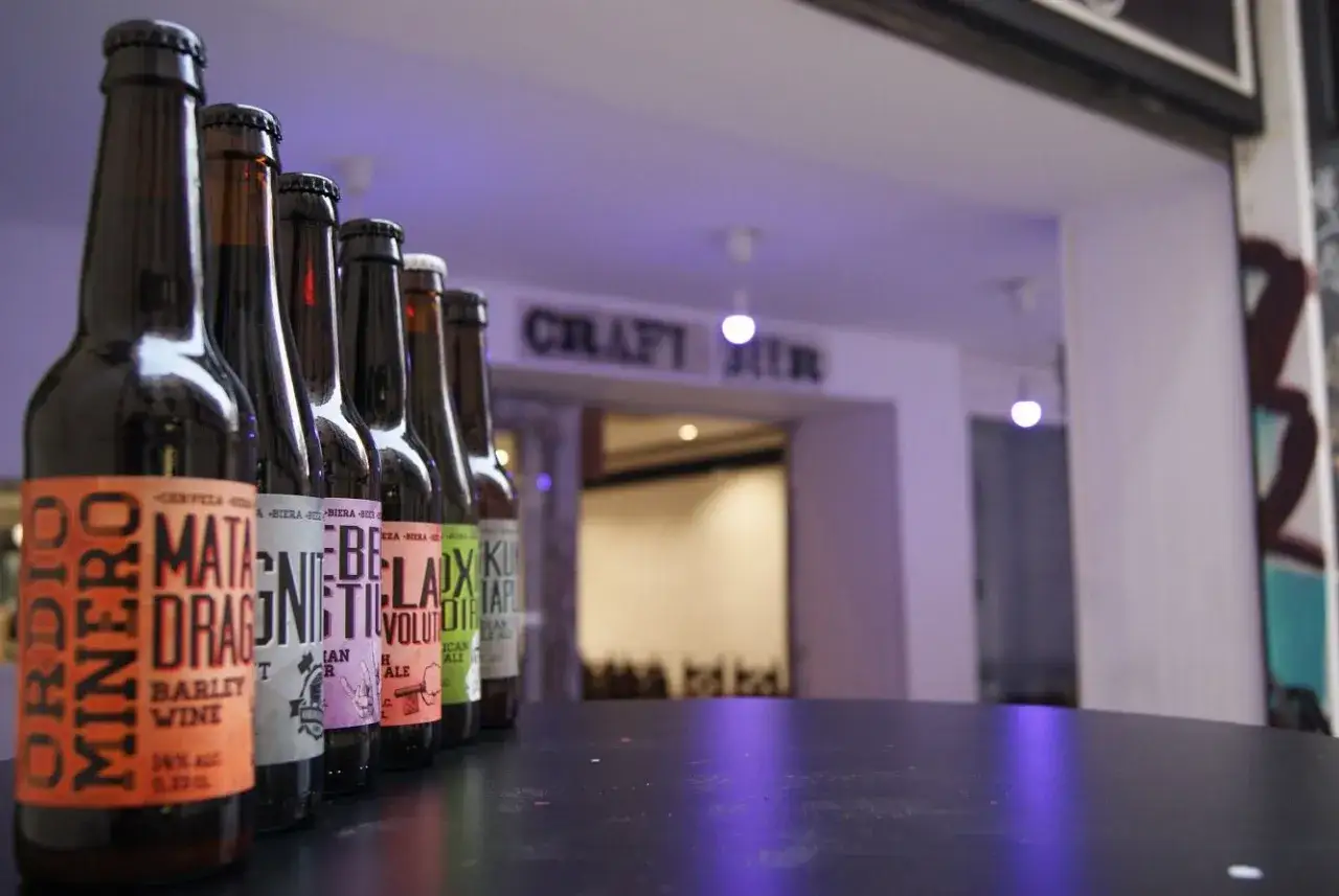 Botellas de birra zaragoza en fila, con etiquetas coloridas. El letrero