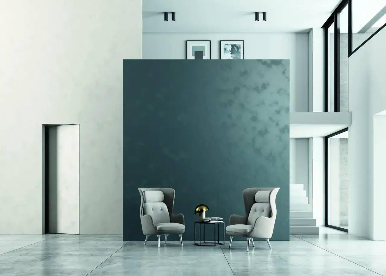 Due poltrone grigie davanti a una parete con pittura effetto sabbiato. Opinioni positive per questo stile moderno e raffinato.