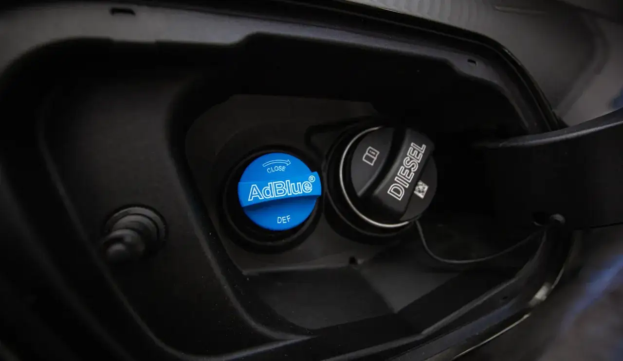 Niebieski korek z napisem AdBlue i DEF obok czarnego korka Diesel. To miejsce tankowania AdBlue, płynu do redukcji emisji spalin.
