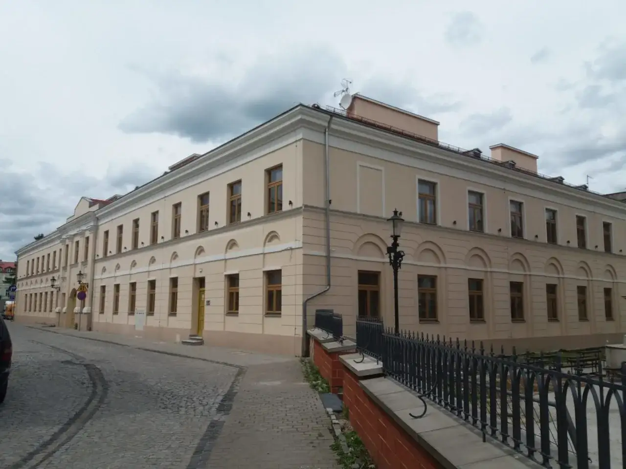 Elegancki budynek w Radomiu, jedna z wielu atrakcji miasta. Ulica brukowana, zabytkowa latarnia.