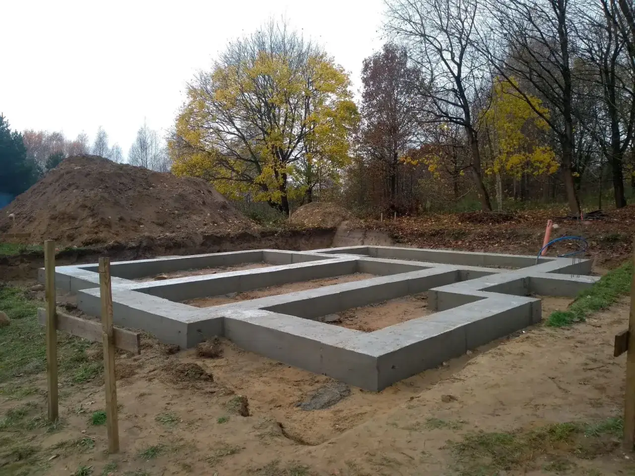 Fundamenty domu w stanie surowym, otoczone jesienną przyrodą. Czy można zostawić odkryte fundamenty na zimę?