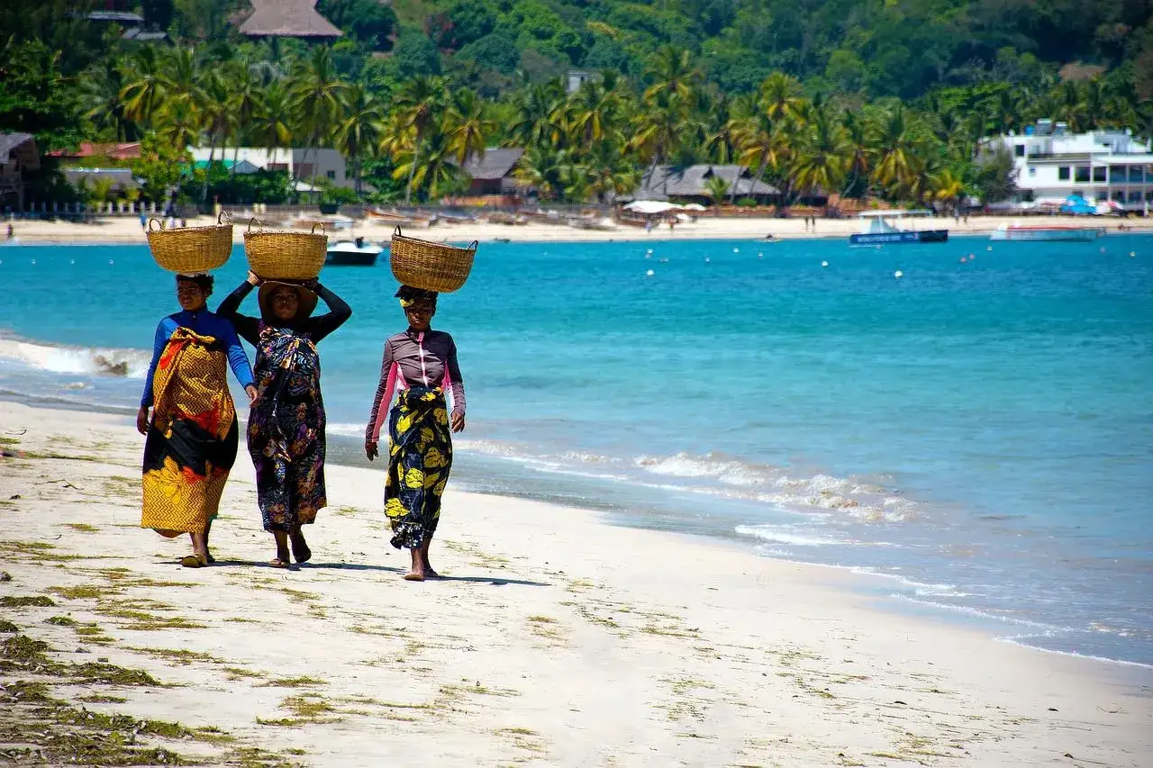 Trzy kobiety niosą kosze na głowach, idąc brzegiem oceanu. Zastanawiam się, ile się leci na Madagaskar, by zobaczyć takie widoki.