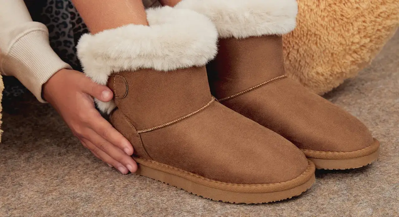 Manos ajustando unas botas de pelo marrones, ideales para aprender como limpiar botas de pelo y mantenerlas perfectas.
