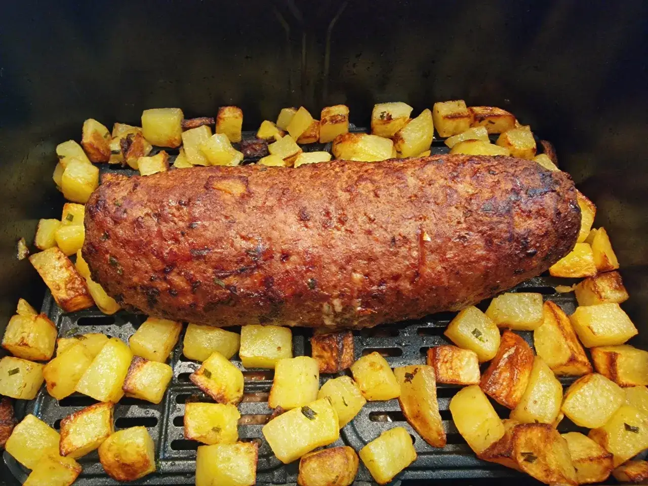 Polpettone succulento e patate croccanti appena sfornati nella friggitrice ad aria.