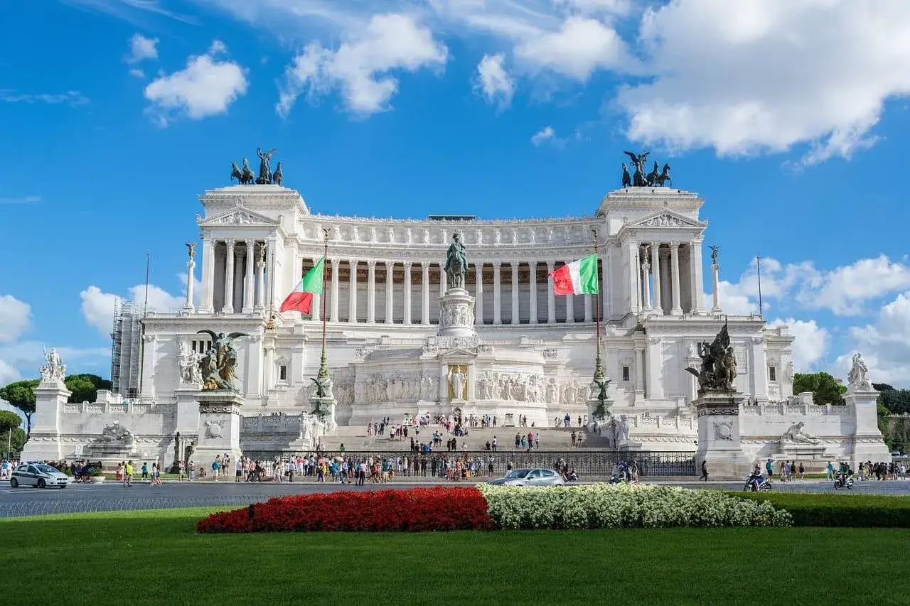 Monumento a Vittorio Emanuele II, simbolo di per cosa è famosa Roma: storia, arte e bandiere italiane sventolano sotto un cielo azzurro.