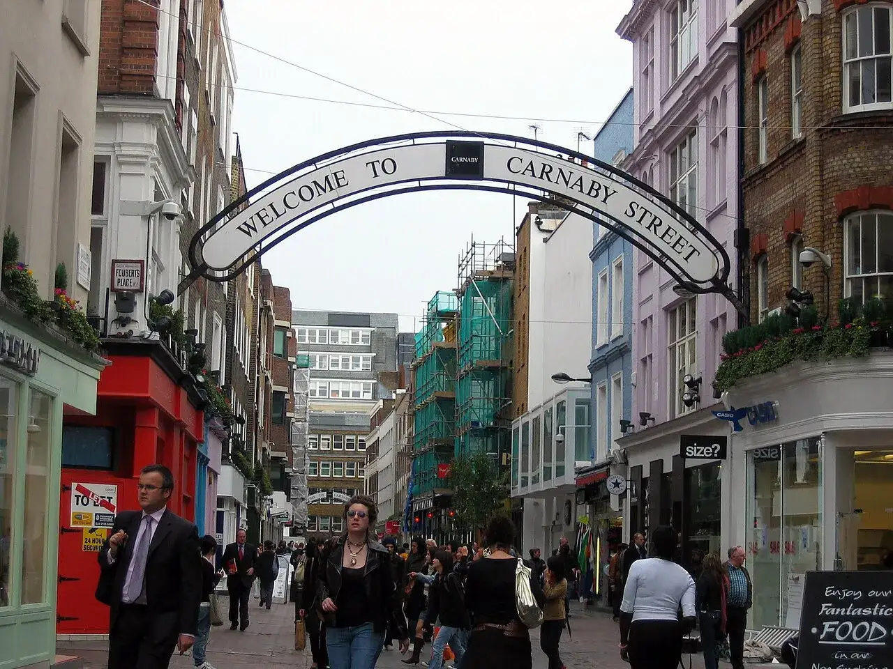 Ludzie spacerują po tętniącej życiem ulicy Carnaby Street, pod łukiem z napisem 