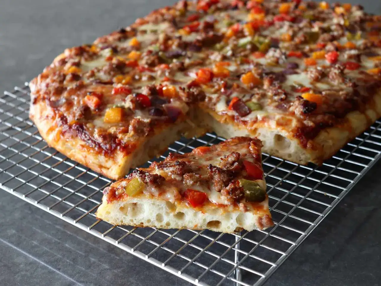 En rektangulär pizza med köttfärs, paprika och lök, som en äkta rome pizza. En bit ligger på ett galler.