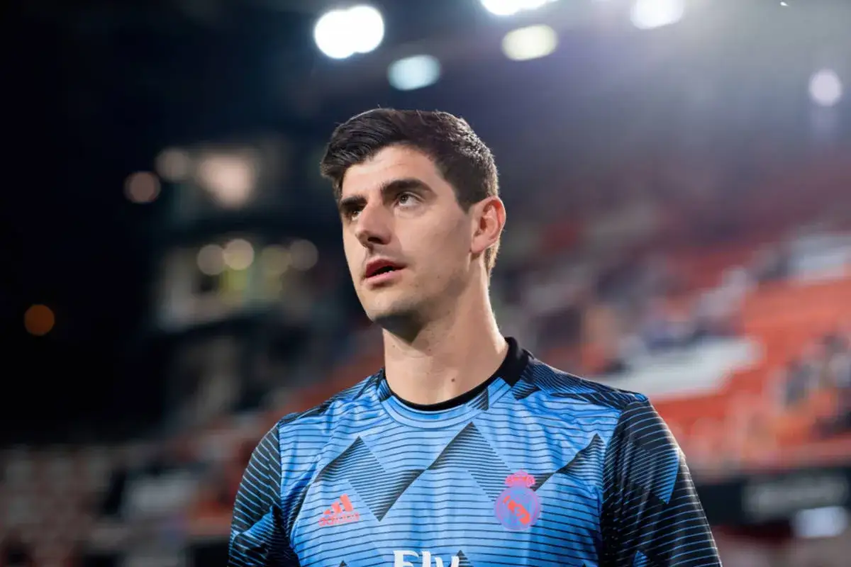 Thibaut Courtois w niebieskiej koszulce Realu Madryt, zaniepokojony, być może po kontuzji.