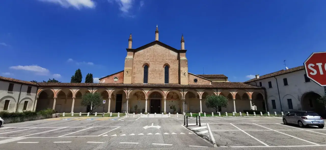 Un esempio di cosa vedere a Cremona in un giorno: la facciata di una chiesa con portico ad archi, sotto un cielo azzurro.