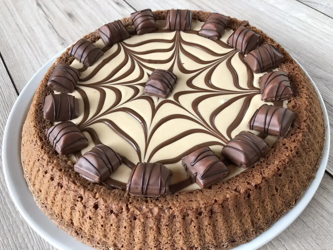 Torta Kinder Bueno con decorazione a ragnatela in crema e cioccolato, guarnita con pezzi di Kinder Bueno.