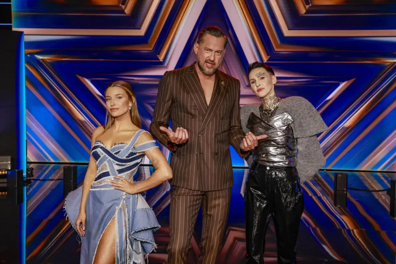 Trójka jurorów Mam Talent: kobieta w jeansowej sukni, mężczyzna w brązowej marynarce i kobieta w srebrnym topie i czarnych spodniach.