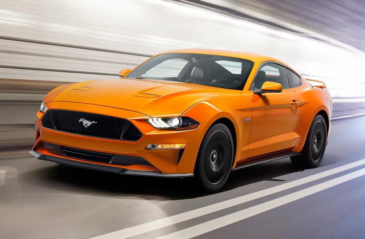 Pomarańczowy Ford Mustang GT 5.0 pędzi przez tunel. Sprawdź aktualną mustang cena i poczuj moc!