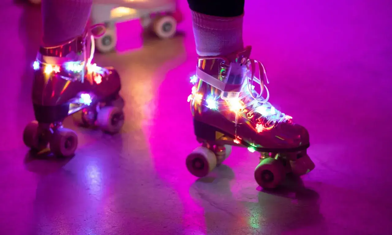 Bunte Lichter schm&uuml;cken Rollschuhe auf einer **Zollverein Rollschuhbahn** im lila Schein.