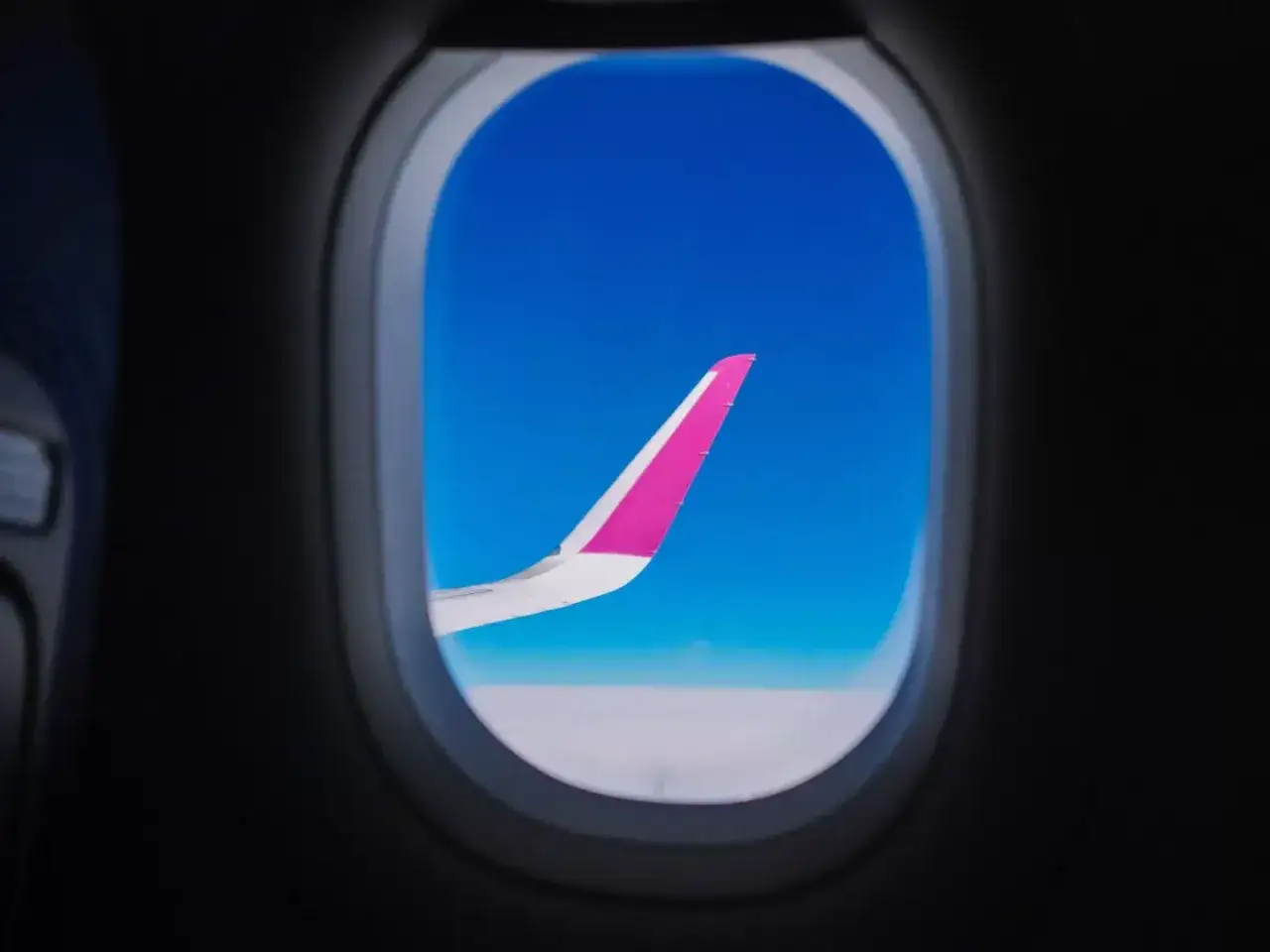 Skrzydło samolotu Wizz Air na tle błękitnego nieba. Dowiedz się, jak zostać członkiem Wizz Discount Club i podróżuj taniej!
