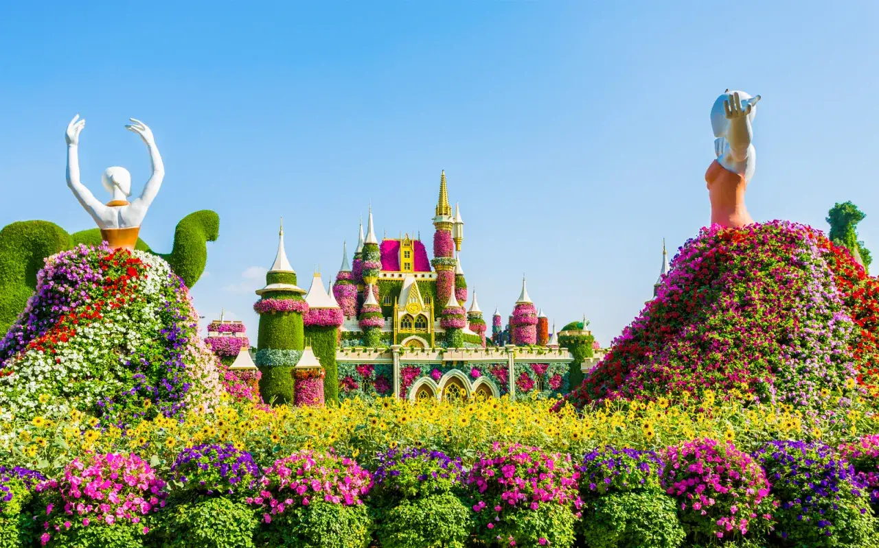 Bajkowy zamek w Miracle Garden w Dubaju, otoczony morzem kwiatów i rzeźbami baletnic.
