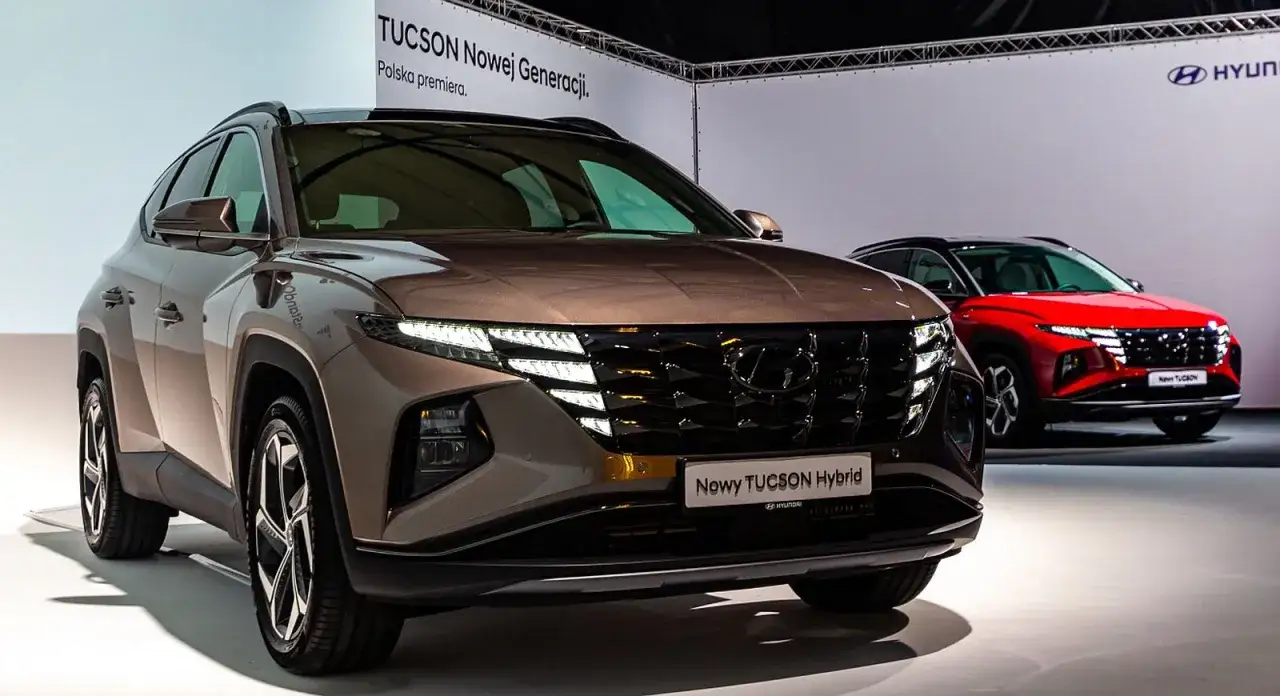 Nowy Hyundai Tucson Hybrid w kolorze brązowym, z przodu czerwony Tucson. Polska premiera nowej generacji.