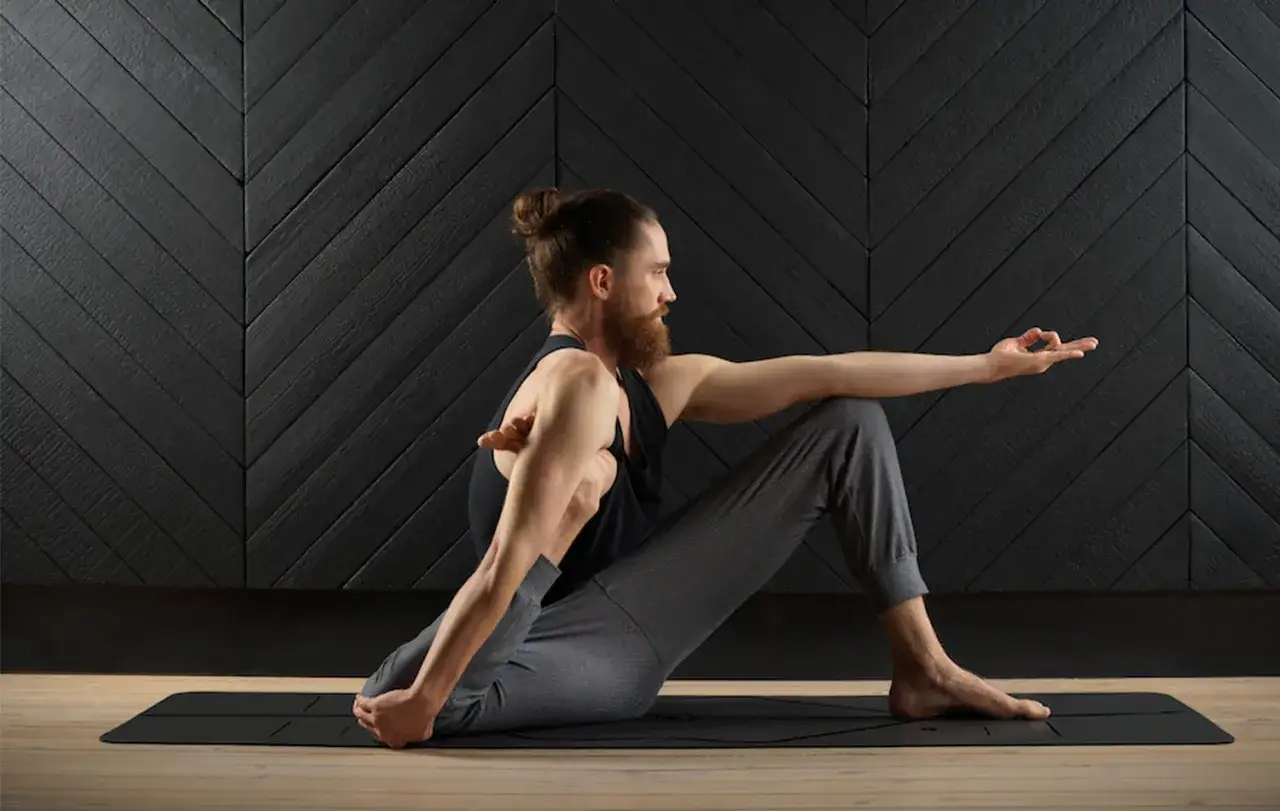 Hombre con barba realiza posturas de yoga avanzadas, girando el torso y extendiendo un brazo.