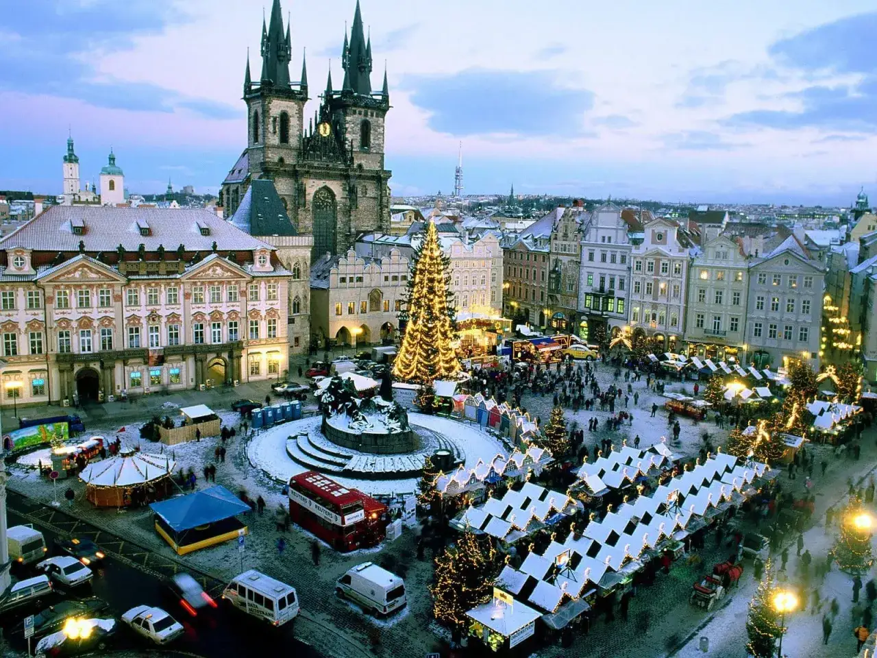 Tłoczny jarmark bożonarodzeniowy Praga z oświetloną choinką i straganami.