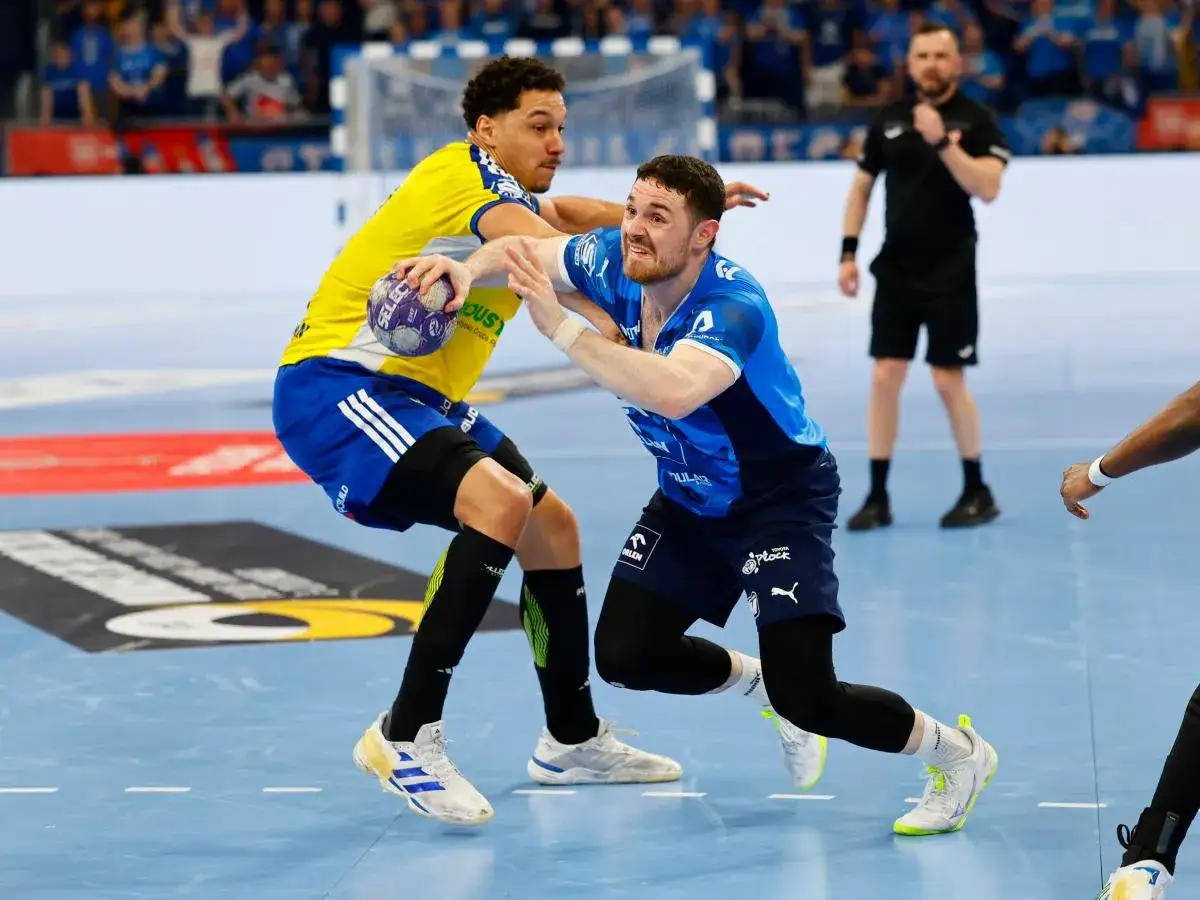 Emocjonująca akcja na parkiecie! Zawodnik w niebieskiej koszulce walczy o piłkę z rywalem w żółtej. Mecz Vive Kielce Wisła Płock w pełni.