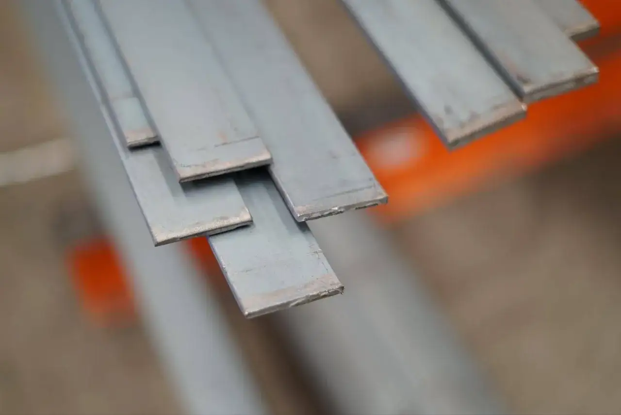 Varias pletinas met&aacute;licas apiladas, listas para ser usadas en construcci&oacute;n o industria.