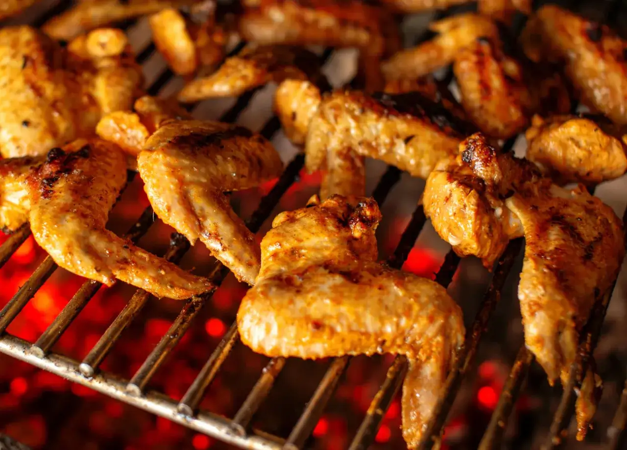 Skrzydełka na grillu, idealnie doprawione marynatą, pieką się nad żarem.