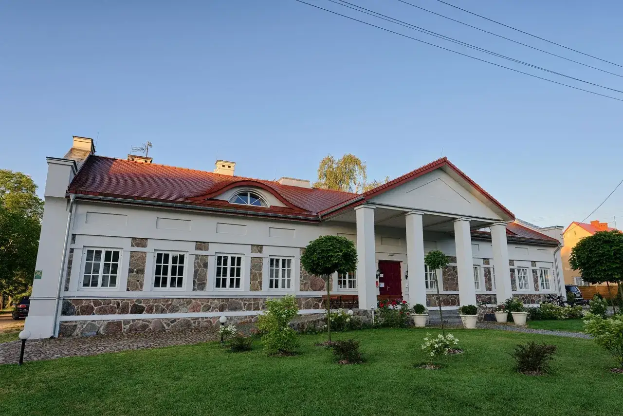 Elegancki pałac w Korczewie z kolumnowym portykiem i kamienną podmurówką, otoczony zadbanym ogrodem.