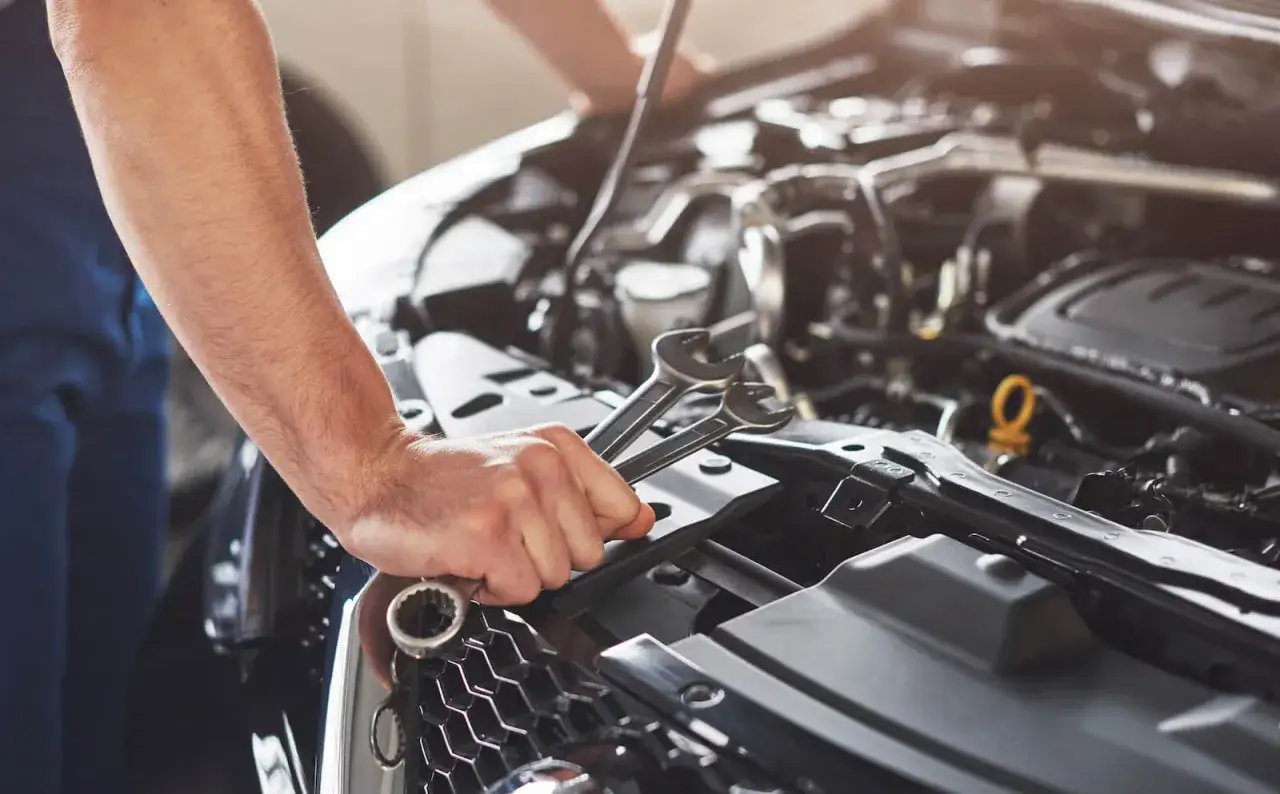 Co zrobić, gdy mechanik przetrzymuje auto? Mechanik z kluczami w ręku przy silniku.